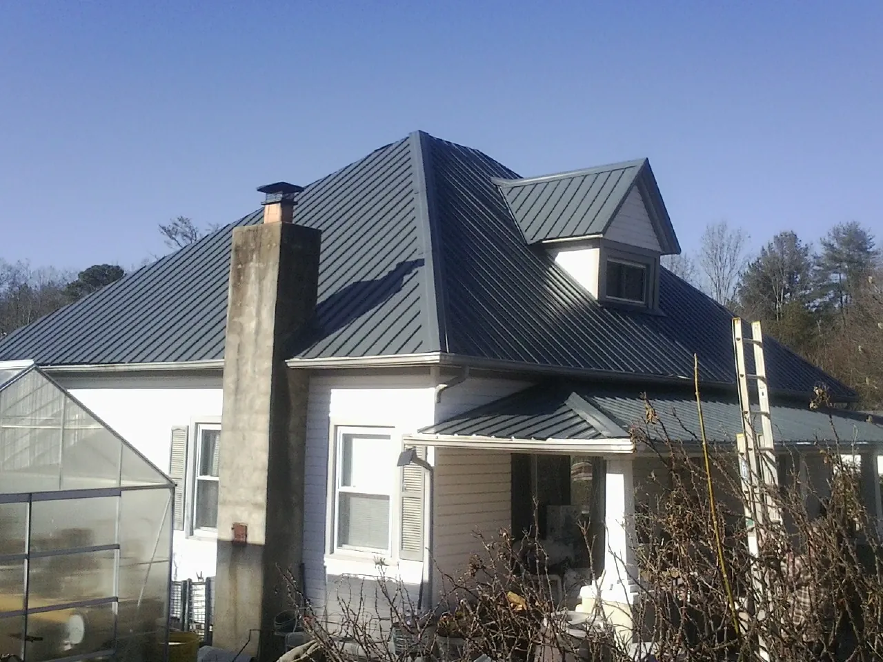 Dark blue standing seam metal roof on a white farmhouse with dormer — Slate & Tile Roof Repair by Roofing Brothers in Helmetta