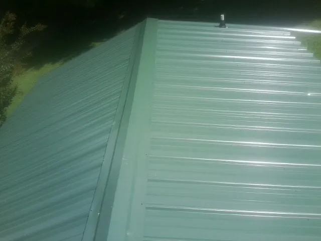 New green metal panels meeting at the ridge of a roof — Flat Roof Repair work by our crew in Helmetta