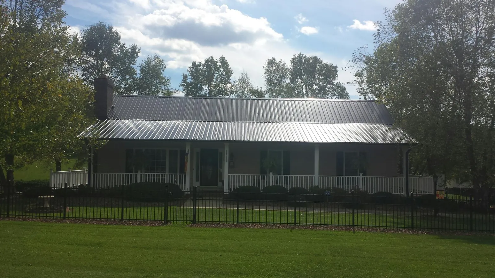 Gray metal roof on a brick ranch with a full width front porch — Gutter Guard Installation work by our crew in Helmetta