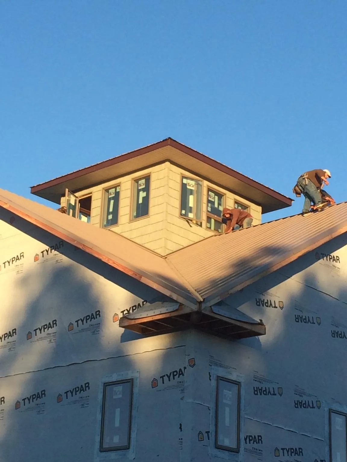 Roofers working around a rooftop cupola on a new metal roof at sunset — Roof Waterproofing in Helmetta by Roofing Brothers